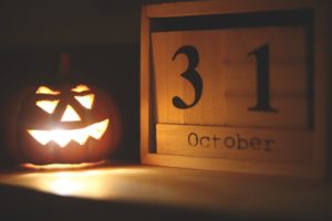 Jack-o-lantern with a light burning inside of it is sitting next to a wooden calendar that says October 31