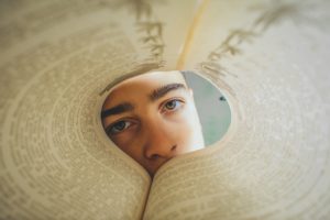 The pages of a book have been bent into a circle. A person's face is staring at you from the other end of that circle.