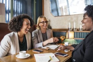 Three people sitting at a booth and laughing. 