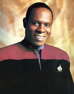 Avery Brooks as Captain Benjamin Sisko in Star Trek: Deep Space Nine. Photo is of Avery smiling while wearing Star Trek uniform. 