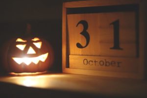 Carved and lit Halloween pumpkin sitting next to a calendar that says October 31