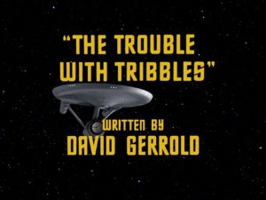Text says The Trouble with Tribbles written by David Gerrold. Image in the background is of the Enterprise from Star Trek: The Original Series. 