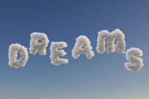 Six clouds digitally altered to spell out the word dreams against a blue sky