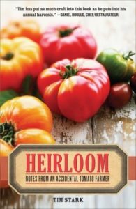 Heirloom- Notes from an Accidental Tomato Farmer by Tim Stark book cover. Image on cover is of green, purple, red, and orange heirloom tomatoes sitting on a wooden table. 
