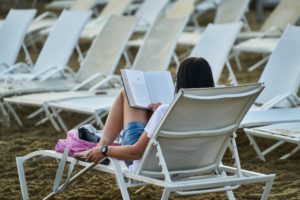 White woman reading a book while sitting in a lawn chair