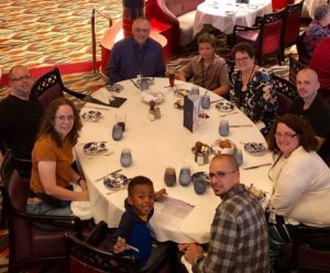 Lydia and her extended family sitting around a large, fancy dinner table.