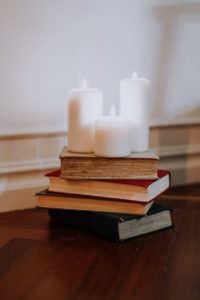 Lit white candles on top of a stack of books. 