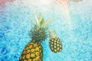 Two pineapples floating in a pool