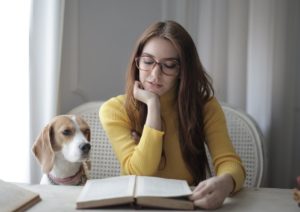 woman reading a book to her dog 