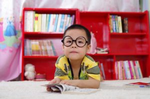 Young boy wearing black, Harry Potter style glasses reading a comic book