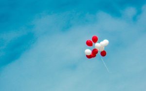 white and red balloons floating away in the sky
