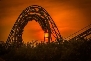 people riding a roller coaster at sunset