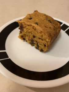 A slice of pumpkin chocolate chip cake on a black and white side plate