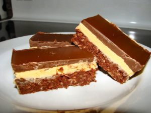Nanaimo bars sitting on a white plate. 