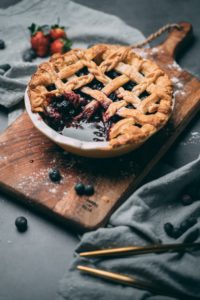 A blueberry pie sitting on a wooden cutting board 