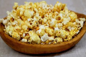 A wooden bowl filled with buttered popcorn 