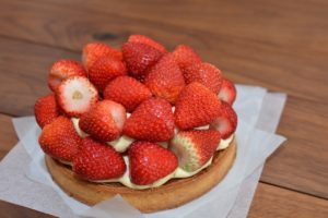 A strawberry tart with whole, fresh strawberries piled on top of it. 