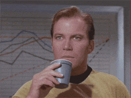 captain kirk from star trek bringing a cup of liquid down from his lips and looking stunned 