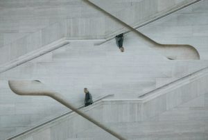 photo of man walking down steps. Upper half of photo shows him walking upside down and up a pair of steps. image might be mirrored or something?