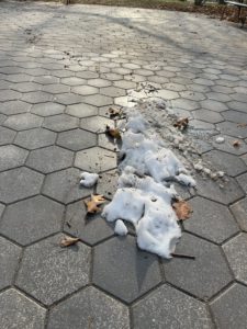 A patch of dirty snow on a sidewalk. 