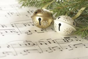 christmas bells hanging from a christmas tree over a sheet of music. 