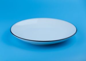 An empty white plate on a blue background 