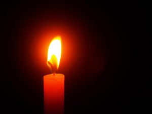 a red lighted candle burning in an otherwise dark room