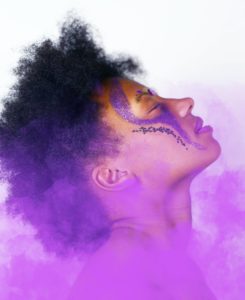 Woman wearing purple face paint and closing her eyes as purple smoke envelops her 