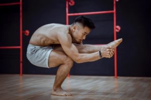 flexible young asian man doing balancing asana during hatha yoga training