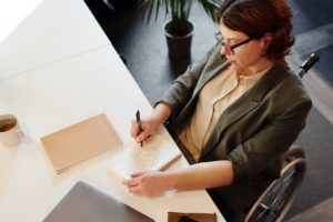 high angle photo of woman writing in a notebook