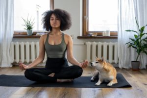 woman meditating while her dog looks on