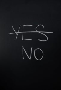 A chalkboard that has the words yes and no written on it. The word yes is crossed out. 