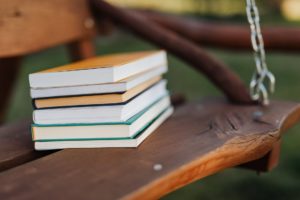 Stack of books on a wooden swing. 