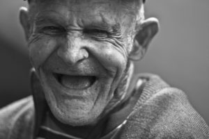 black and white photo of an elderly man who is laughing. 