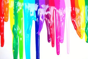 Multicolored paint dripping down a white background