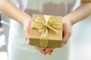Woman holding a gift wrapped in gold paper and a gold ribbon 