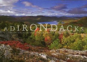 Adirondacks- Views of An American Wilderness by Carl E. Heilman II book cover. Image on cover is panoramic shot from a mountaintop to the lush forest and lake below. 