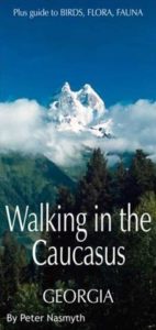 Walking in the Caucasus - Georgia by Peter Nasmyth book cover. Image on cover shows mountain covered in clouds and snow peeking above a thick forest of pine trees.