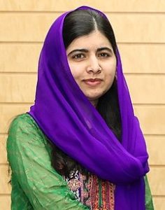 Photo of Malala Yousafzai wearing a green dress and a purple headscarf 