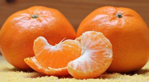 peeled tangerine next to two whole tangerines 