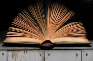 An open book lying spine down and pages fanned out while letting on a metal table. 