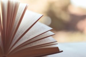 Book with opened pages sitting on a windowsill.