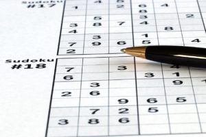 Close-up photo of a ballpoint pen lying on a sheet of Sudoku puzzles