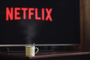 Photo of mug near flat screen tv that has the word Netflix on it. 