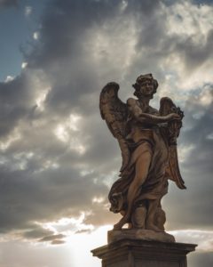 Photo of a stone angel surrounded by stormy grey clouds
