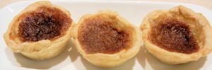 Three butter tarts on a white serving platter 