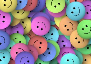 Smiley faces of many different hues lying on top of each other. 