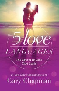 The 5 Love Languages: The Secret to Love that Lasts by Gary Chapman book cover. Image on cover shows a couple embracing on a beach as the sun sets behind them. 
