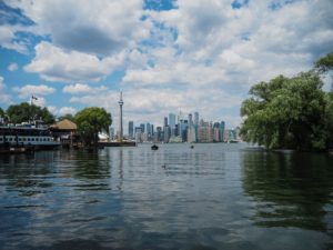 Toronto Ferry at Toronto island. The CN tower and the city landscape are in the backrground. It is a semi-cloudy summer day and the lake water is nice and placid. 