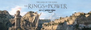 The Lord of the Rings The Rings of Power tv show poster. It shows a city carved from stone that’s protected by a large stone statute holding it’s hand out benevolently. 